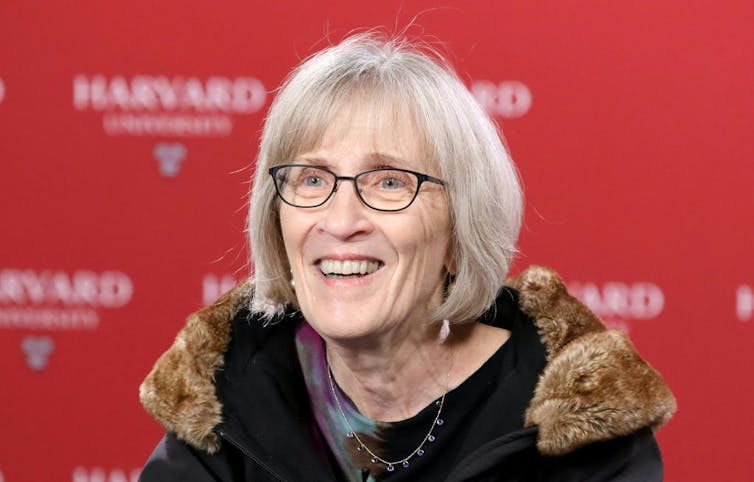 woman with white hair and glasses smiling.