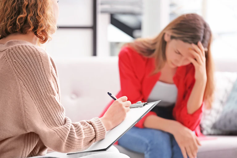 Consultation entre une adolescente se tient la tête face à une personne adulte qui