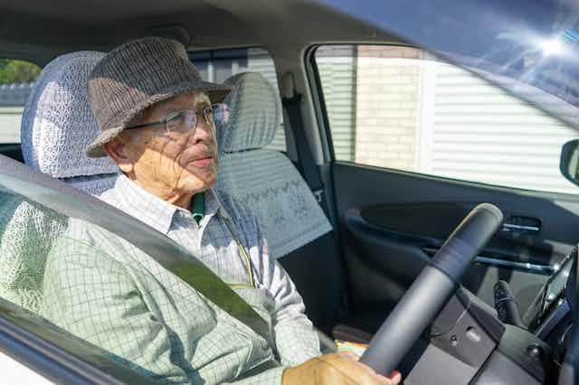 an older stylish gentleman sits in a car