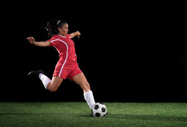 A leg kicks a soccer ball.