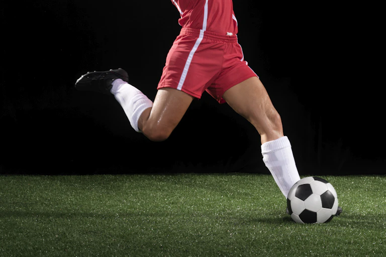 A leg kicks a soccer ball.