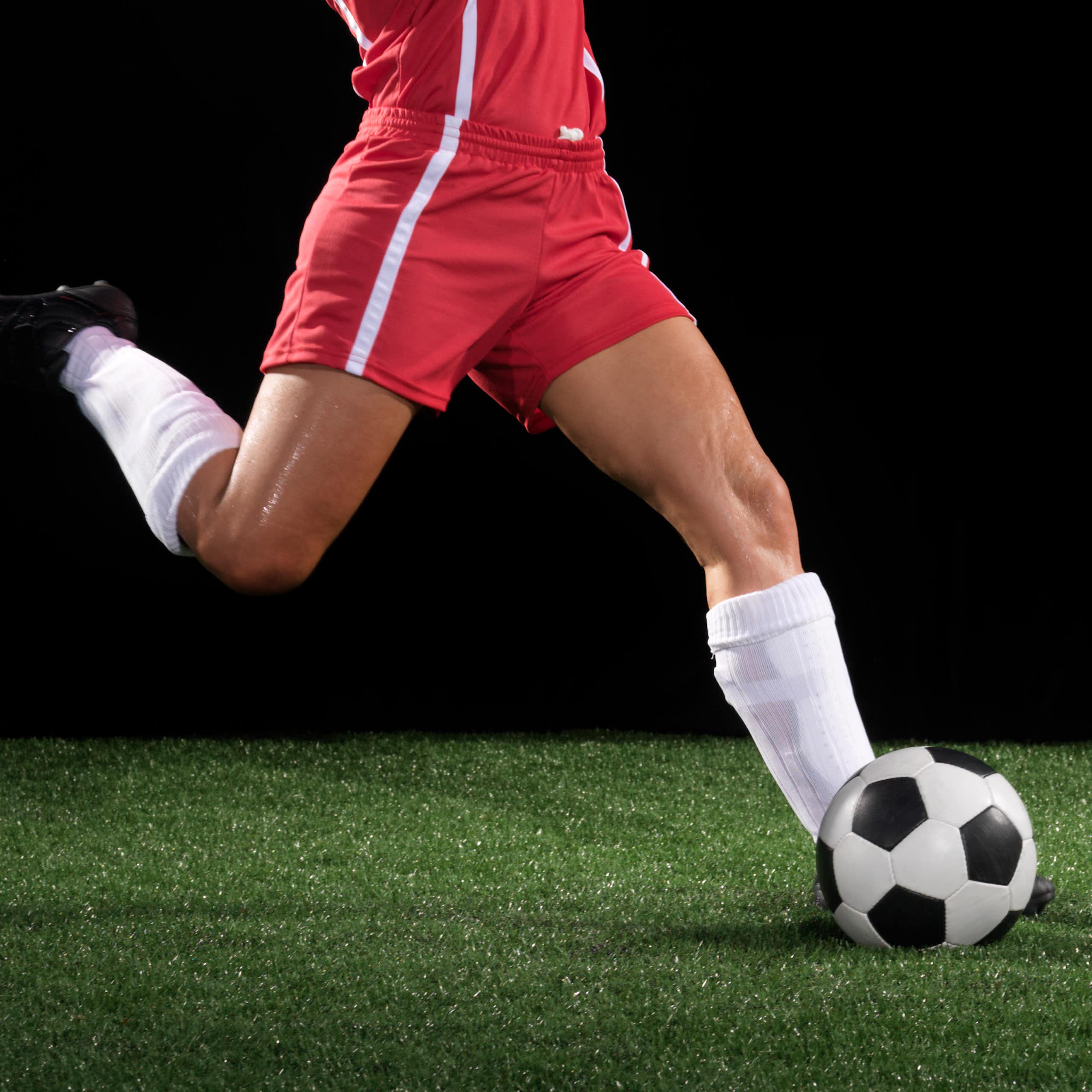 A leg kicks a soccer ball.