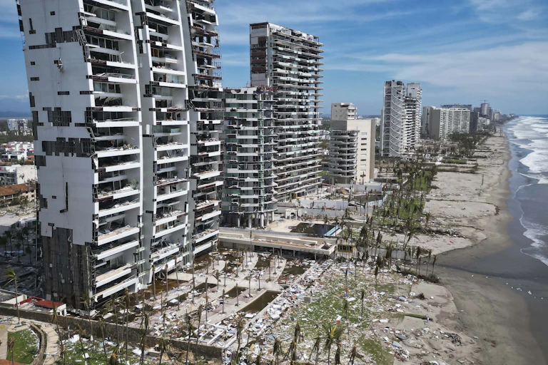 A row of high-rises with windows blown out and material missing from the sides.