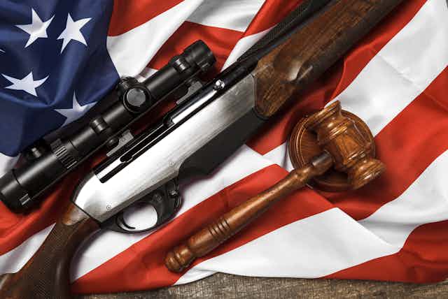 An illustration of a hunting rifle and a judge's gavel resting on an American flag.