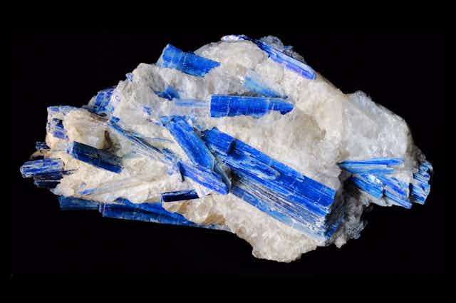 A large chunk of quartz studded with long , bright blue crystals