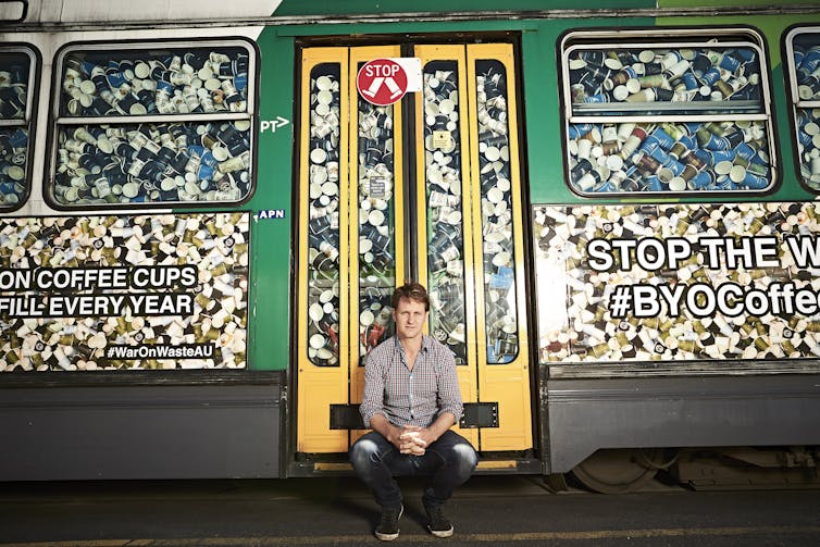 Craig Reucassel with a Melbourne tram filled with 50,000 disposable coffee cups