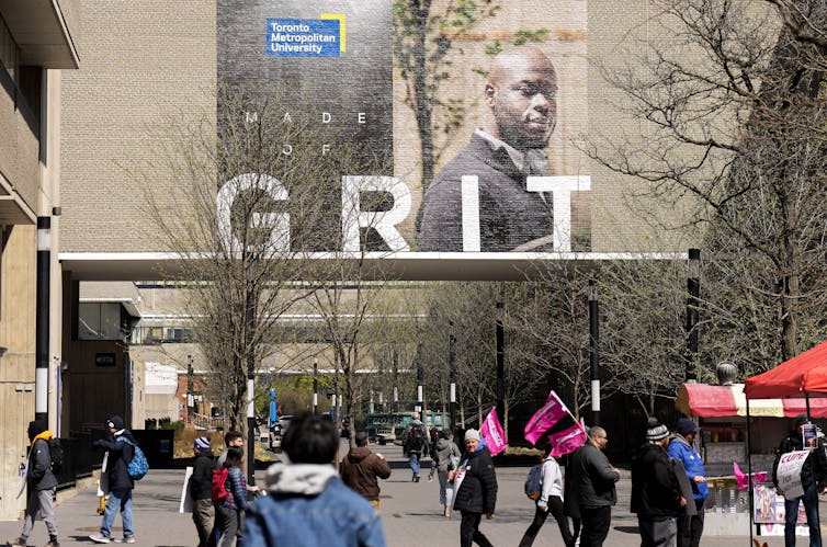 Students mingle underneath a large sign that reads Grit.