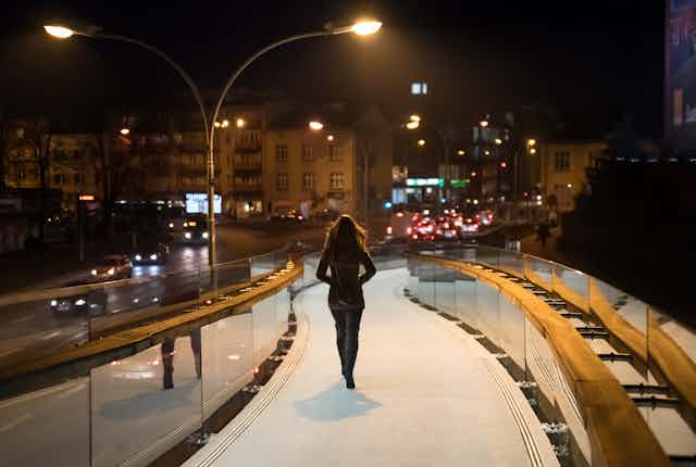A woman walks in a city in the dark