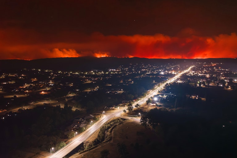 Aerial night view of town with bushfire on the horizon