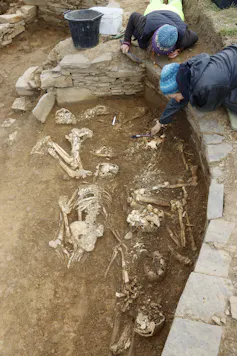 Two people digging around the skeletons