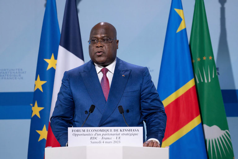 A man speaking at a podium with flags behind him