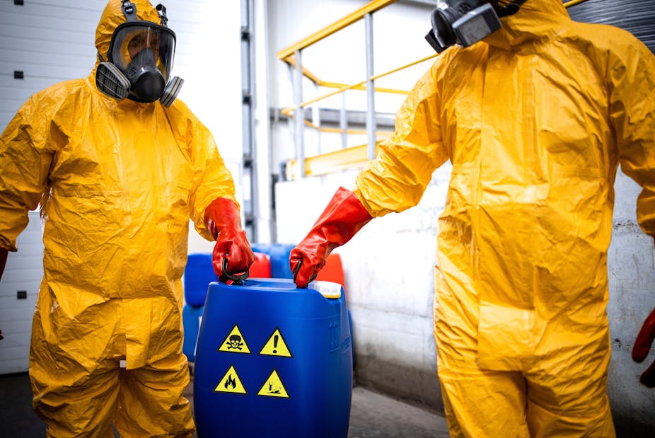 Workers in a chemical production factory carry toxic waste