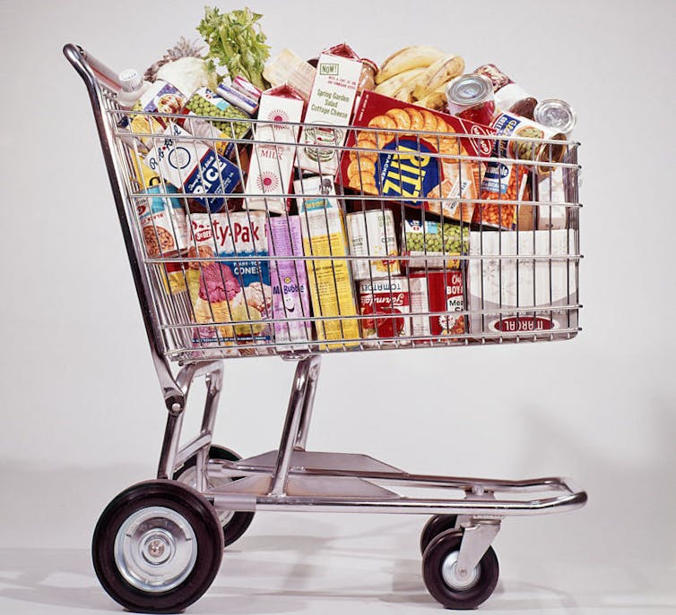 A shopping cart filled with colorfully packaged food products.