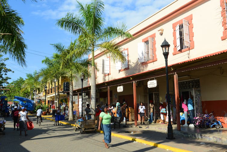 A woman walks along a shopping strip.