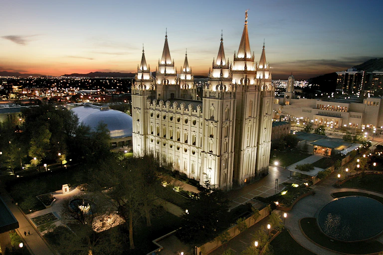 A castle-like church, illuminated, at night in a downtown area.