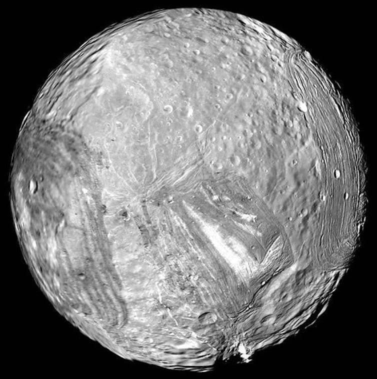 A black and white photo of a pockmarked moon of Uranus.