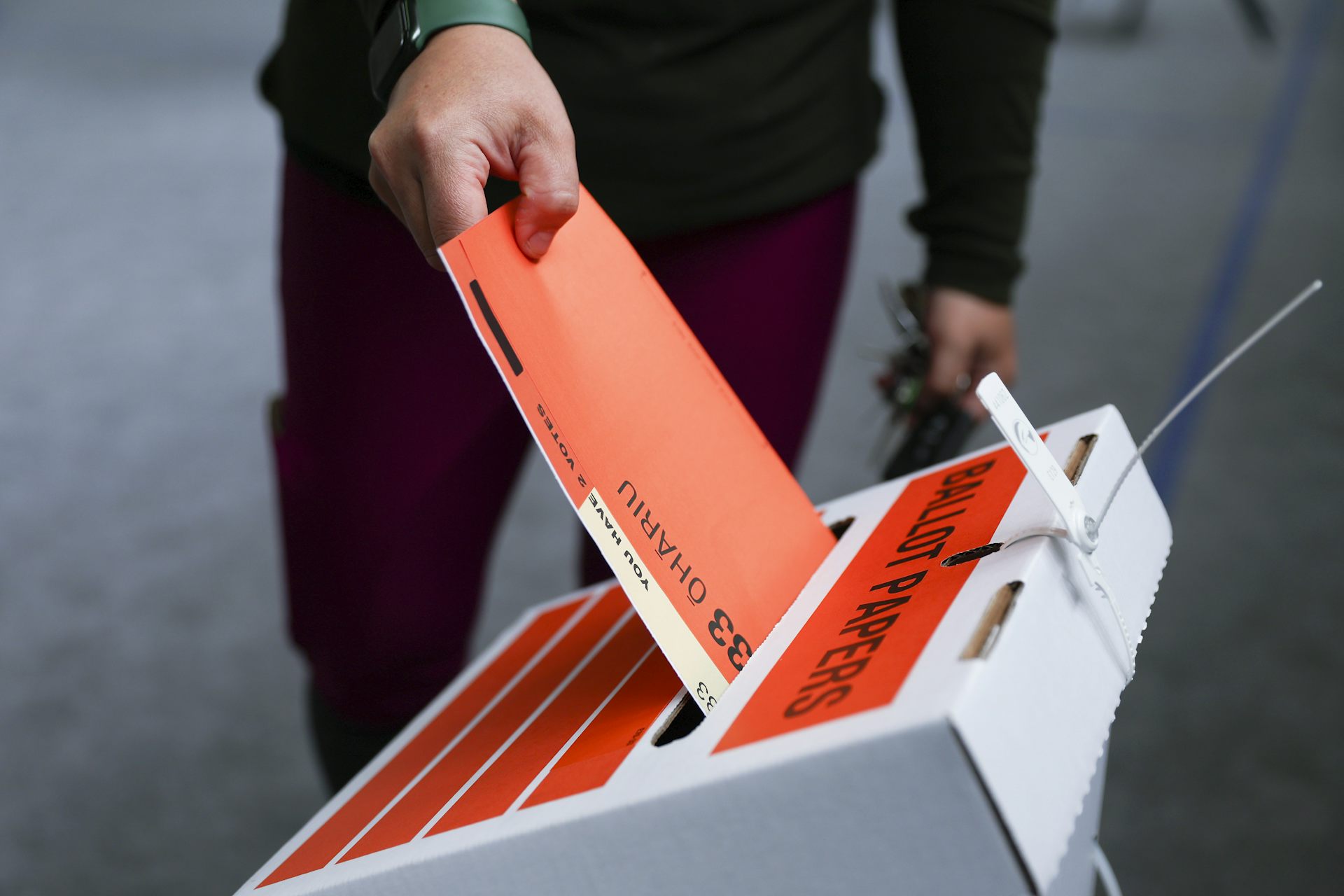 Voter putting election ballot into ballot box.