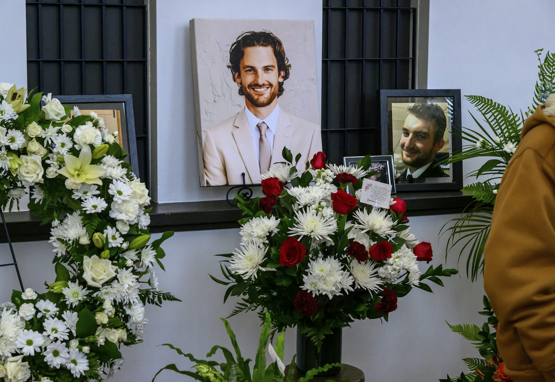 A photo of a young, smiling man surrounded by flowers