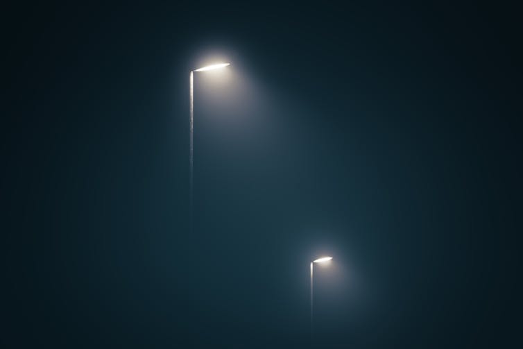 Two streetlights light up a dark, misty night