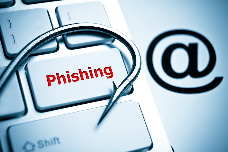 A concept image featuring a keyboard on which the word "phishing" is written with a fishing hook laid atop it, alongside an "at" symbol