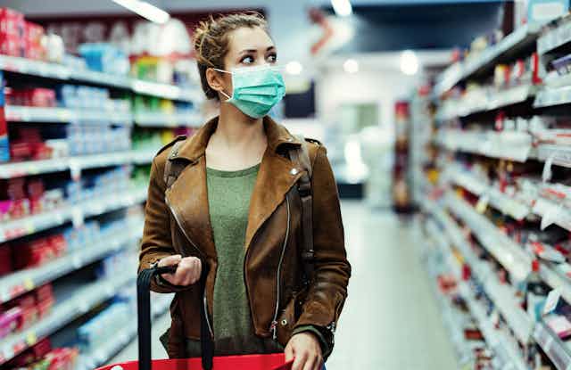 Woman in mask looks at supermarket shelf