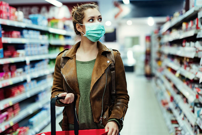 Woman in mask looks at supermarket shelf