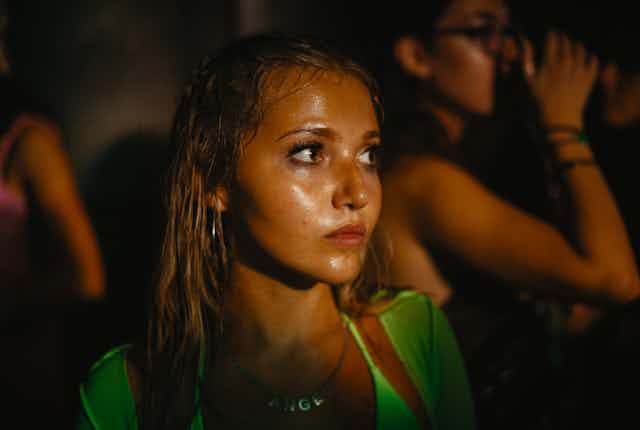 A young girl's face is lit by the light from a stage