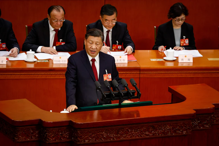 Xi Jinping speaks during the Closing Session of the National People's Congress with CCP officials taking notes behind him.