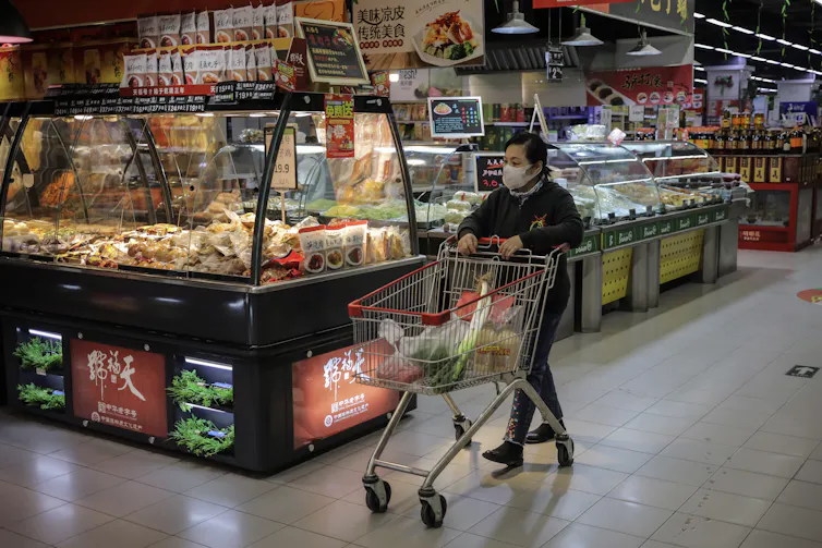 A Chinese woman walks around a supermarket ikn Baijing 2021.