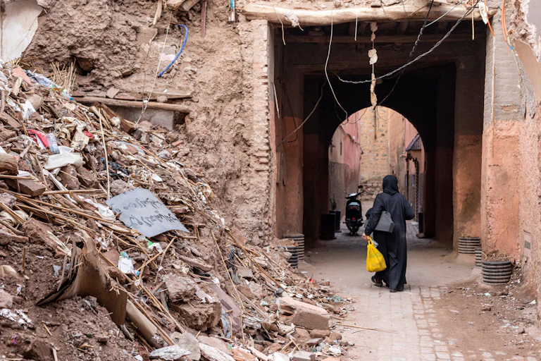 A woman walks past a pile of rubble in Marrakech's old medina.
