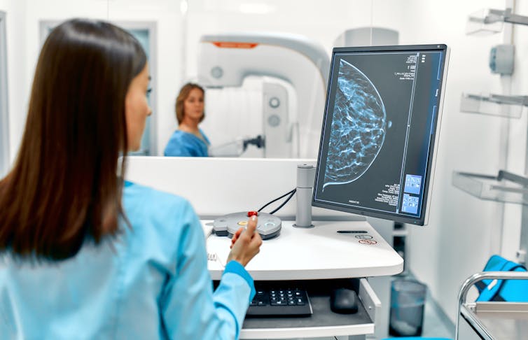 A nurse looks at a breast cancer scan on a computer screen.
