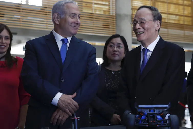 Two men in suits smile on a tour of a facility.