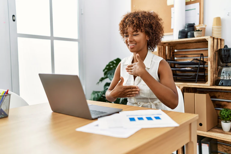 A young Black woman uses sign language while on a video call