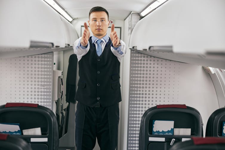 A flight attendant directs passengers to the nearest available exits.