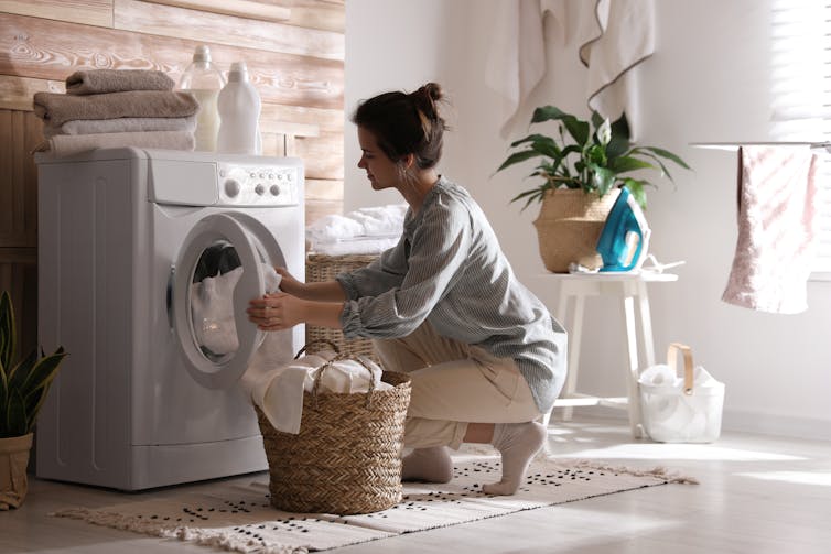 A young woman loading a washing machine.