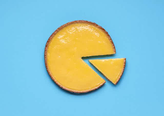A lemon curd pie with a slice taken out on a light blue background