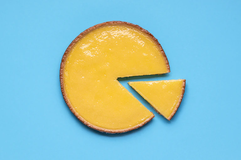 A lemon curd pie with a slice taken out on a light blue background