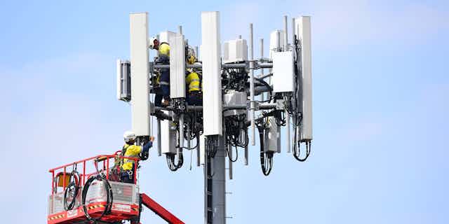 Telecommunications workers are seen working on a mobile cell tower