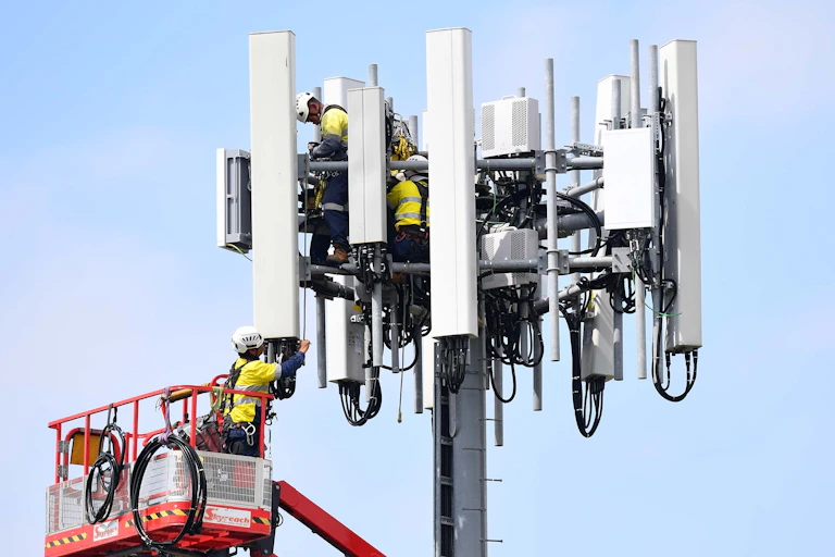 Telecommunications workers are seen working on a mobile cell tower