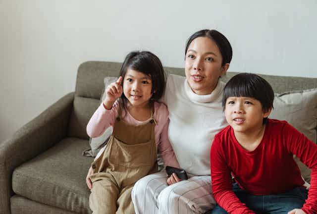 A woman and two young children sit on a couch.