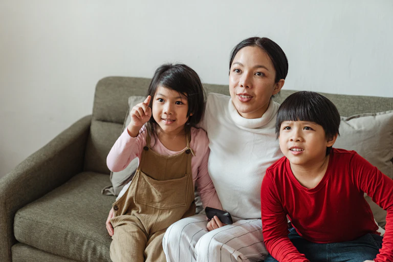 A woman and two young children sit on a couch.