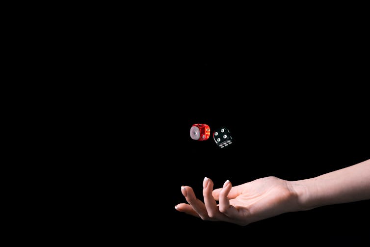 Image of hand rolling dices isolated on black background.