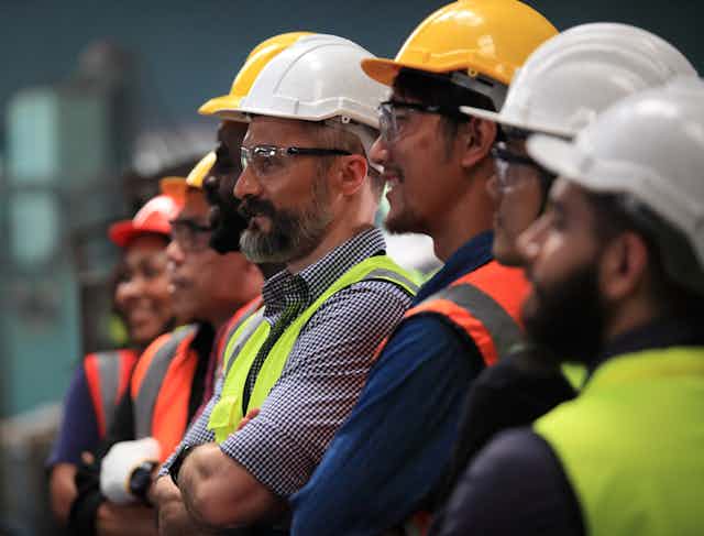 Workers with hard hats on standing in a line.