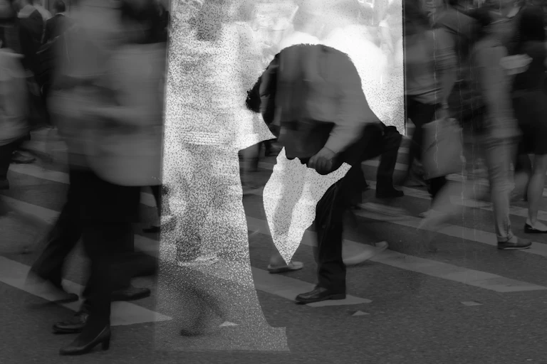A photo of a person in despair set against a background of people walking in a city.
