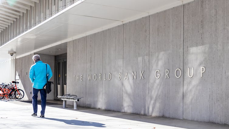 A man walks past a building with 'World Bank Group' in tall letters on the exterior.