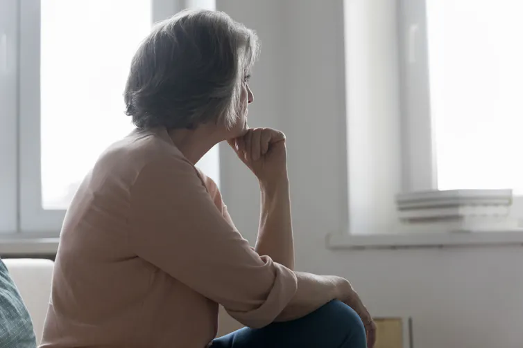 A woman sitting down looks into the middle distance.