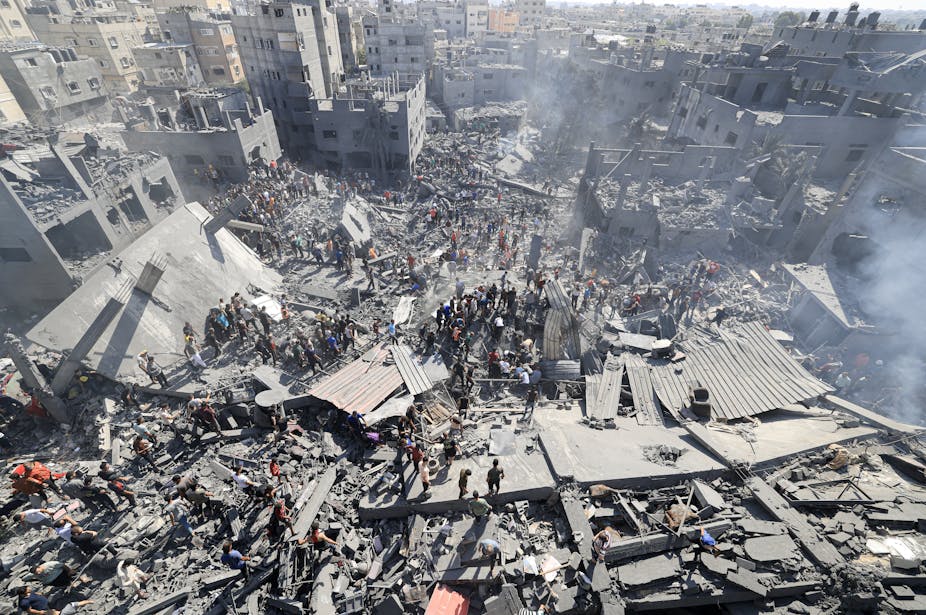 Des gens se rassemblent dans les décombres d'un immeuble détruit
