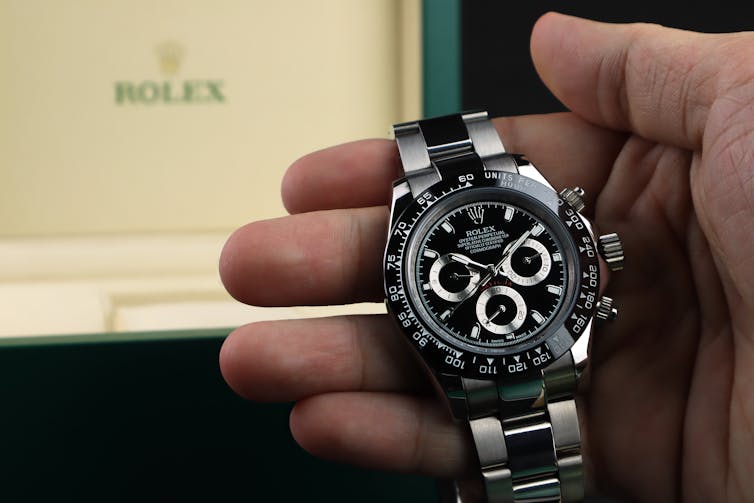 A man holding a Rolex watch.