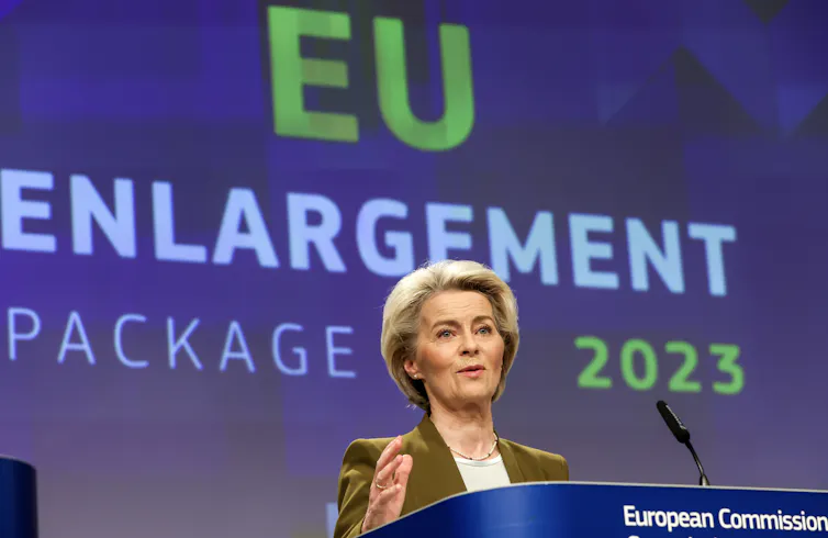 Ursula von der Leyen speaking at a lectern in front of a screen that bears the words 'EU Enlargement Package 2023'