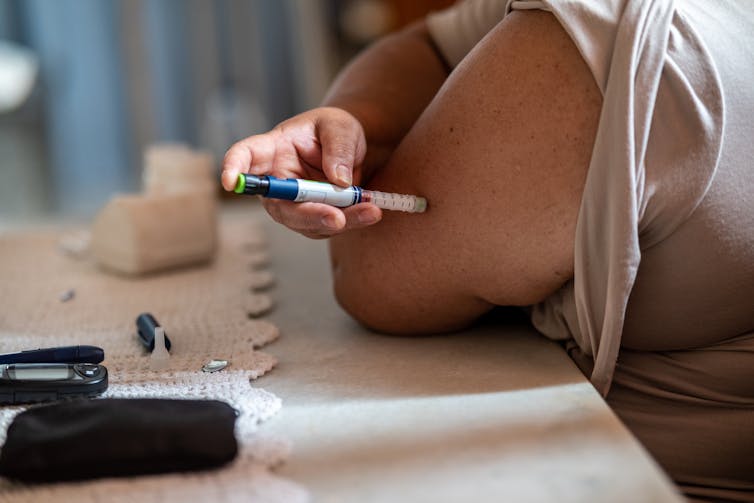 Primer plano de una persona inyectándose insulina en el brazo